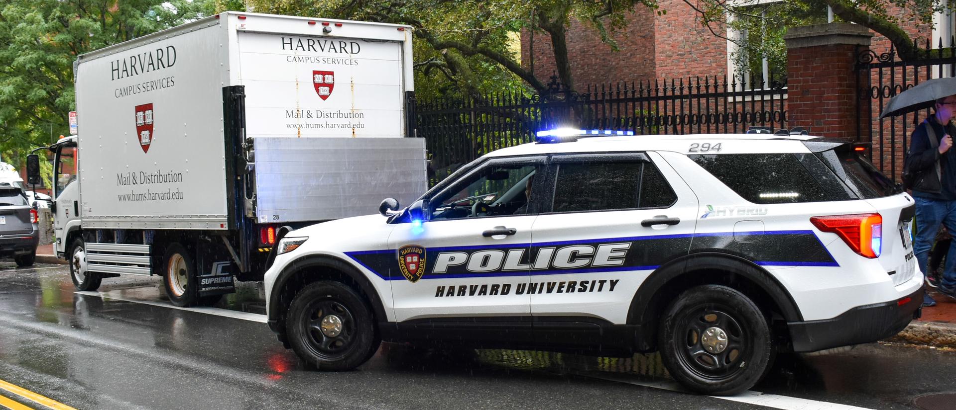 Harvard University Police car with a Harvard University Mail Services truck.